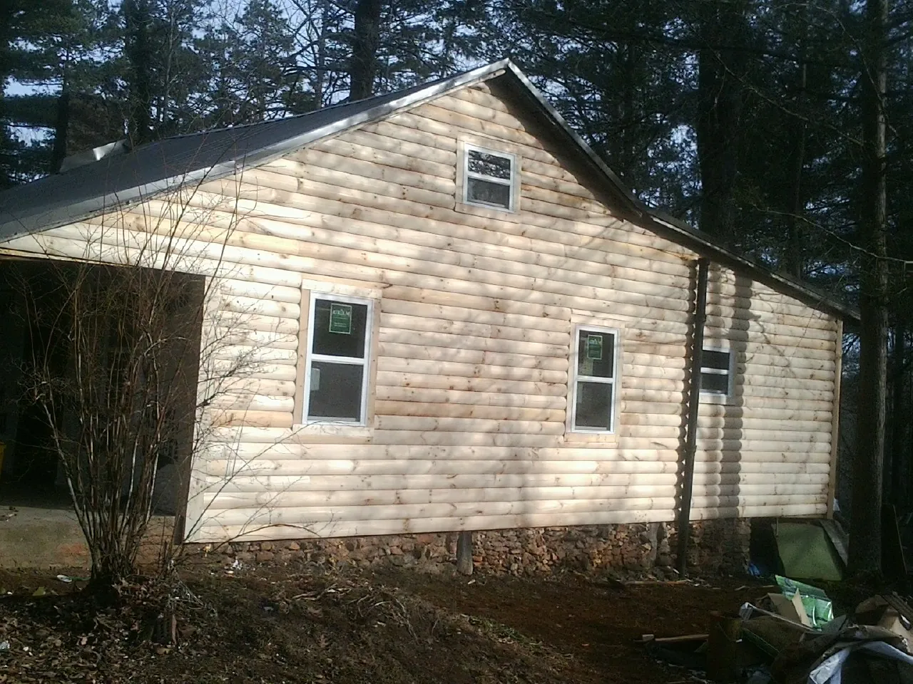 New log siding and dark metal roofing on a gable end in Zwingle