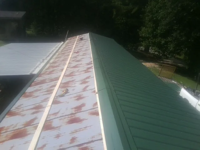 Old rusted panels beside newly installed green metal roofing — Wind Damage Roof Repair by Roofing Brothers in Zwingle