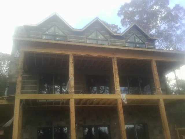 Dormers and porch framing on a large log home under construction — Roof Coating work by our crew in Zwingle