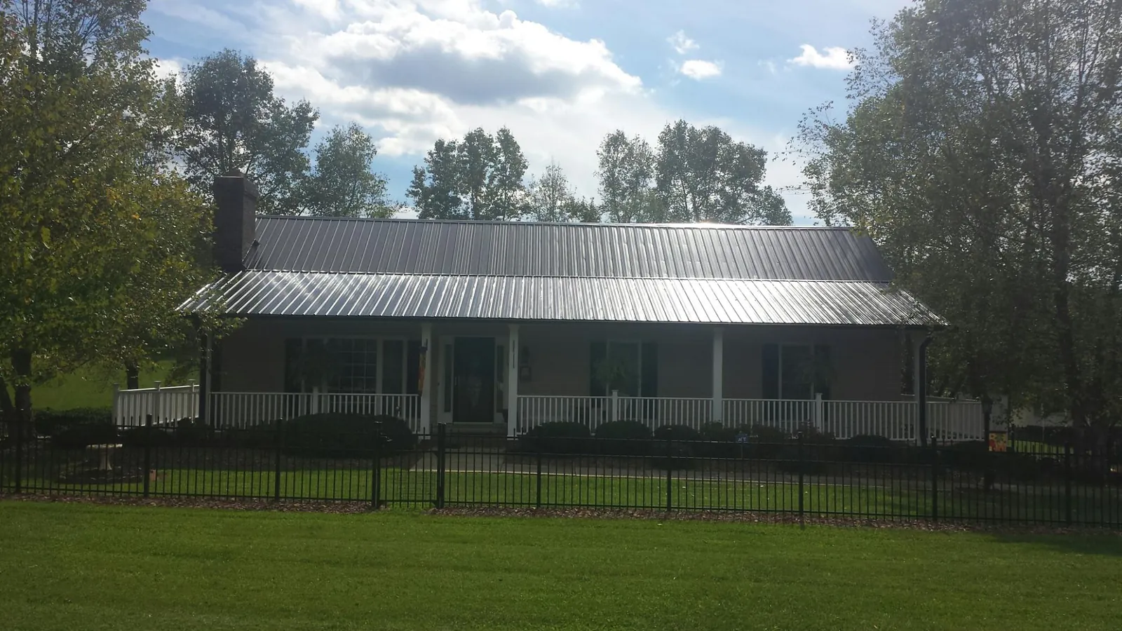Gray metal roof on a brick ranch with a full width front porch — Gutter Guard Installation work by our crew in Zwingle