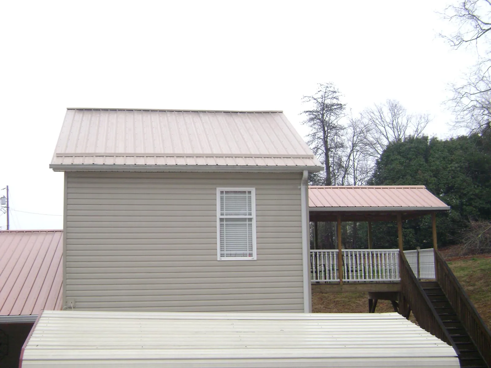 Tan metal roofs on a two story addition and attached porch, from a Roof Replacement job in Zwingle