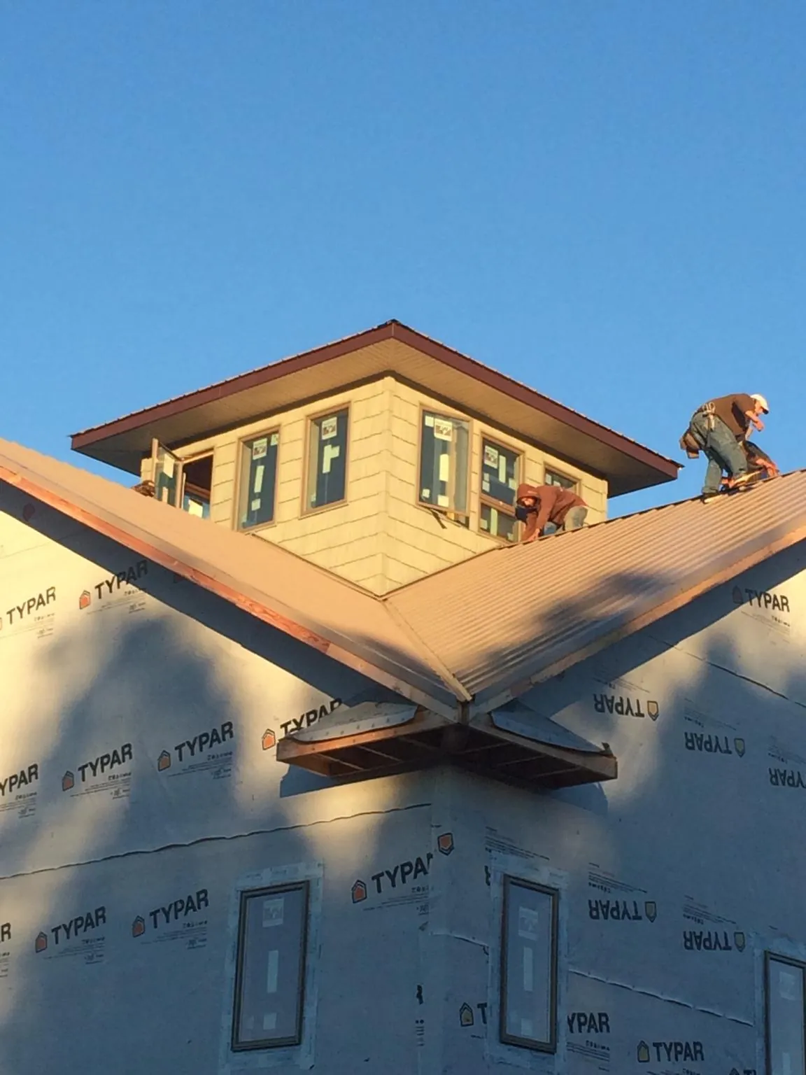 Roofers working around a rooftop cupola on a new metal roof at sunset — Roof Waterproofing in Zwingle by Roofing Brothers